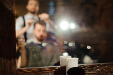 Master cuts hair and beard of men in the barbershop