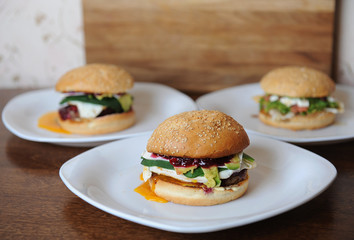 Burgers on white plates on a wooden background