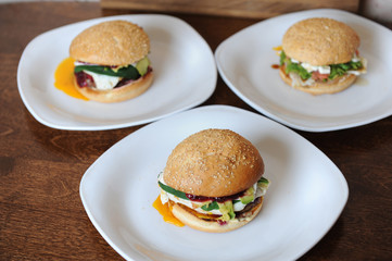 Burgers on white plates on a wooden background