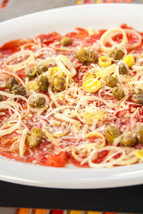 Salmon carpaccio with lemon, onion and olives.