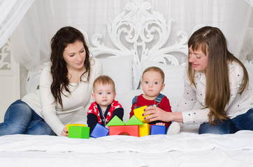 Two mothers with young boys playing with colored cubes