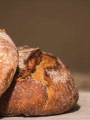 closeup of handmade tasty bread lying on table covered by white cloth with gray background