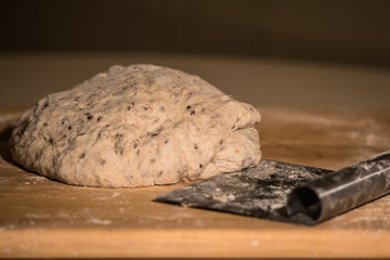 the dough on wooden cutting board with metal instrument prepared for making bread