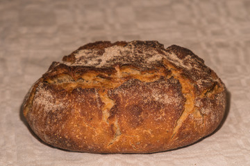 a loaf of handmade bread with amazing texture laying on white old cotton cloth