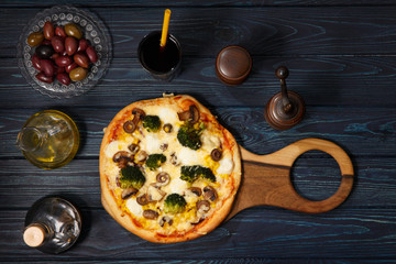 Homemade vegetarian pizza on the dark wooden table, top view.