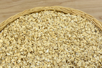Raw uncooked heap of instant oatmeal cereal ln wicker plate