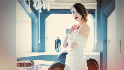 beautiful young woman standing near the table in the light luxury room