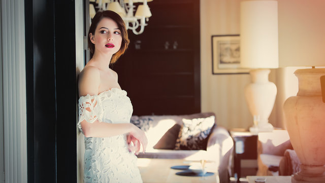 beautiful young woman standing near the door in the light luxury room and looking somewhere