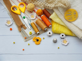 Composition of yellow accessories for needlework on wooden background. Knitting, embroidery, sewing. Small business. Income from hobby.