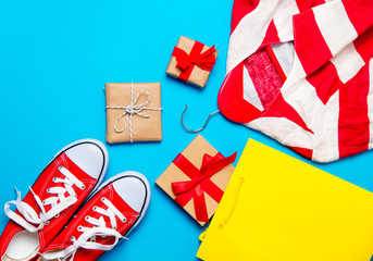 Fototapeta premium big red gumshoes, cool shopping bag, striped jacket on hanger and beautiful gifts on the wonderful blue background
