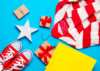 Fototapeta na wymiar big red gumshoes, cool shopping bag, striped jacket on hanger, star shaped toy and beautiful gifts on the wonderful blue background