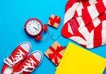 Fototapeta premium big red gumshoes, cool shopping bag, striped jacket on hanger, alarm clock and beautiful gifts on the wonderful blue background