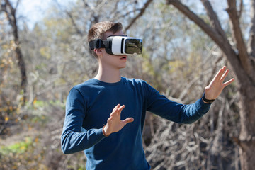 Naklejka premium Young man wearing virtual reality glasses, standing in a park