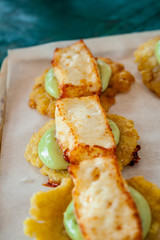 Cheese and avocado tostones, plantain crushed in small portions. In the top a fried cheese. - 138503760