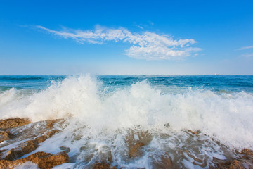 Huge wave breaking over rocks with dramatic foam and brilliant sea coast line morning