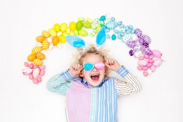 Child on Easter egg hunt. Pastel rainbow eggs.