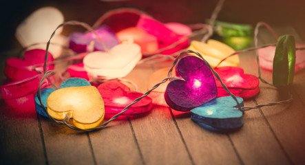 beautiful colorful heart shaped garland lying on the wonderful brown wooden background