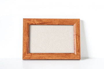Blank wooden photo frame on the shelf	near the wall