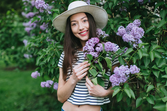 Portrait of stylish hipster girl among blossoming lilac.
