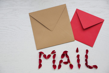 Word "Mail".  Love Letter with Flowers on White Wooden Background. Beautiful flowers in envelope on wooden background. Spring mood concept. Romantic gift with love flowers.