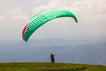 Sporty young man getting ready to fly paraglider