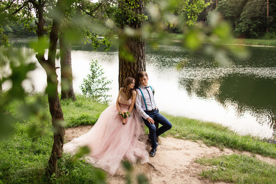 Newlyweds couple in love sitting on bench near lake. Beautiful landscape for wedding day