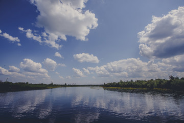 Damme, Belgium. Beautiful riverscape in village at daytime. Dutch polder landscape near the village  with a windmill and a canal with some colorful covered boats on a sunny day in the fall season.