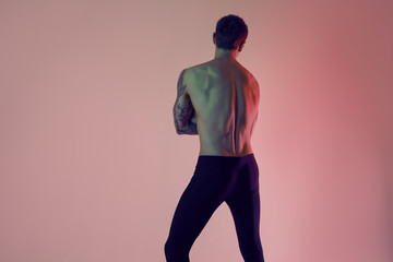 Sexy sporty sport fit man. Muscular naked torso from back on a red background.