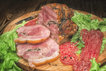 meat and salami with herbs on a cutting board