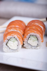 Philadelphia sushi roll with red fish on a white plate