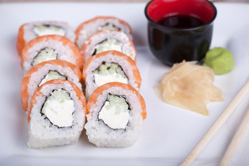 Philadelphia sushi roll with red fish on a white plate