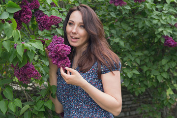 Beautiful woman in garden among the lilacs. People