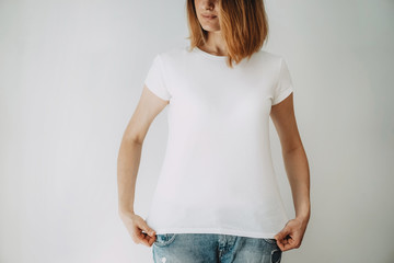 Young hipster girl wearing blue jeans and blank white t-shirt with area for your logo or design,...