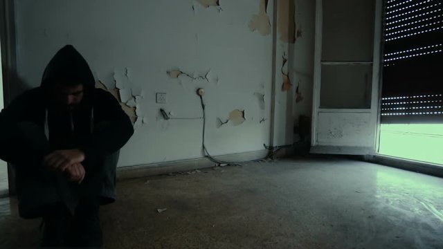 Hooded depressed young man in empty abandoned house