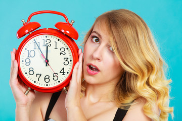 Shocked girl with alarm clock on blue.