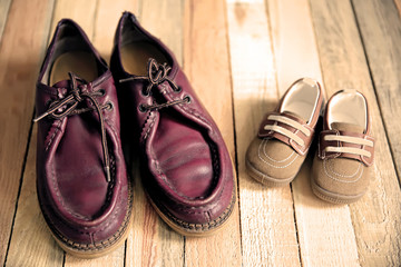 Shoes for father and son on wooden background