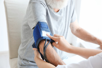 Nurse helping senior with measuring pressure at home
