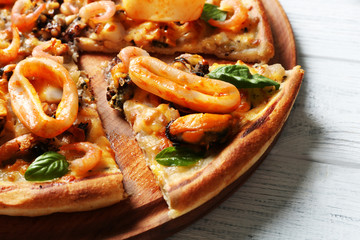 Tasty sliced pizza with seafood on wooden tray