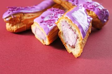 Delicious glazed eclairs on red background