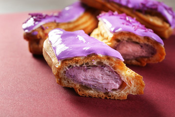 Delicious glazed eclairs on red background