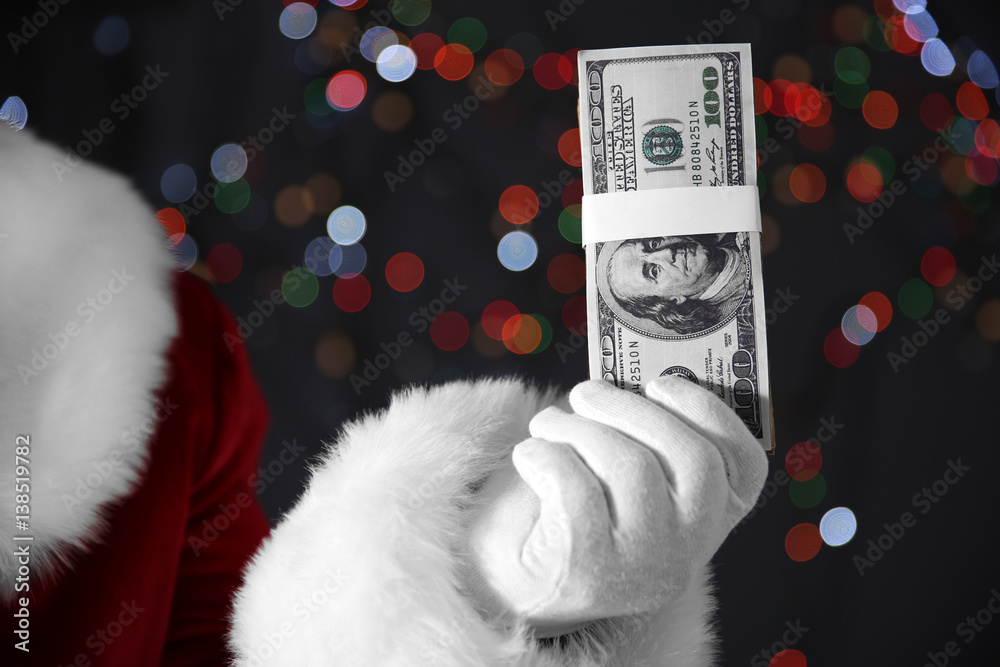 Poster santa claus hand holding money on blurred lights background