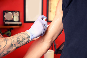 Tattoo master in studio applying antiseptic onto skin