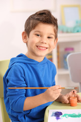Cute little boy drawing picture and sitting at table, closeup