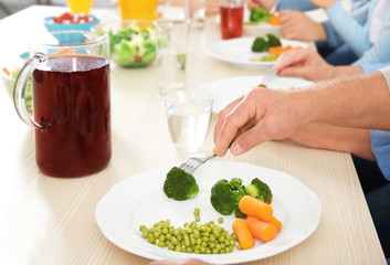 Man eating vegetables during lunch at home, closeup