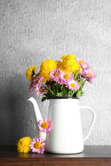 Beautiful bouquet of flowers in kettle  on color background