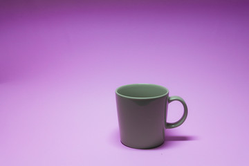 Brown coffee cup on purple background.