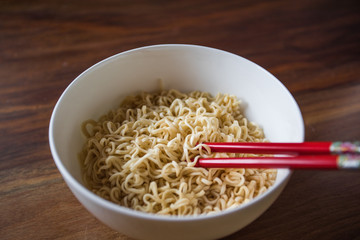 White Bowl of Japanese Ramen Noodles With Red Chopsticks on Wooden Table