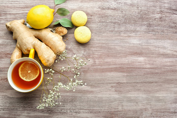 Cup of tea with lemon, ginger and macaroons on wooden background