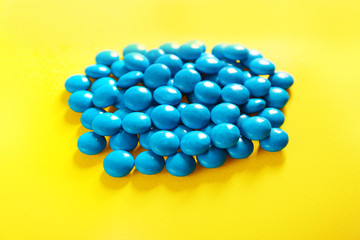 Blue candies on yellow background