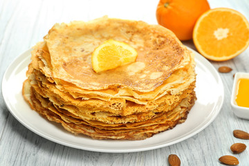 Stack of delicious pancakes with orange on wooden table